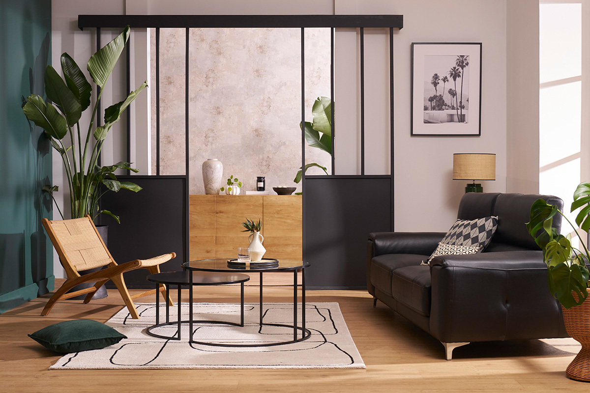 Fauteuil lounge YARI en bois teck et corde, angle avec canap� noir, plante verte et table basse.