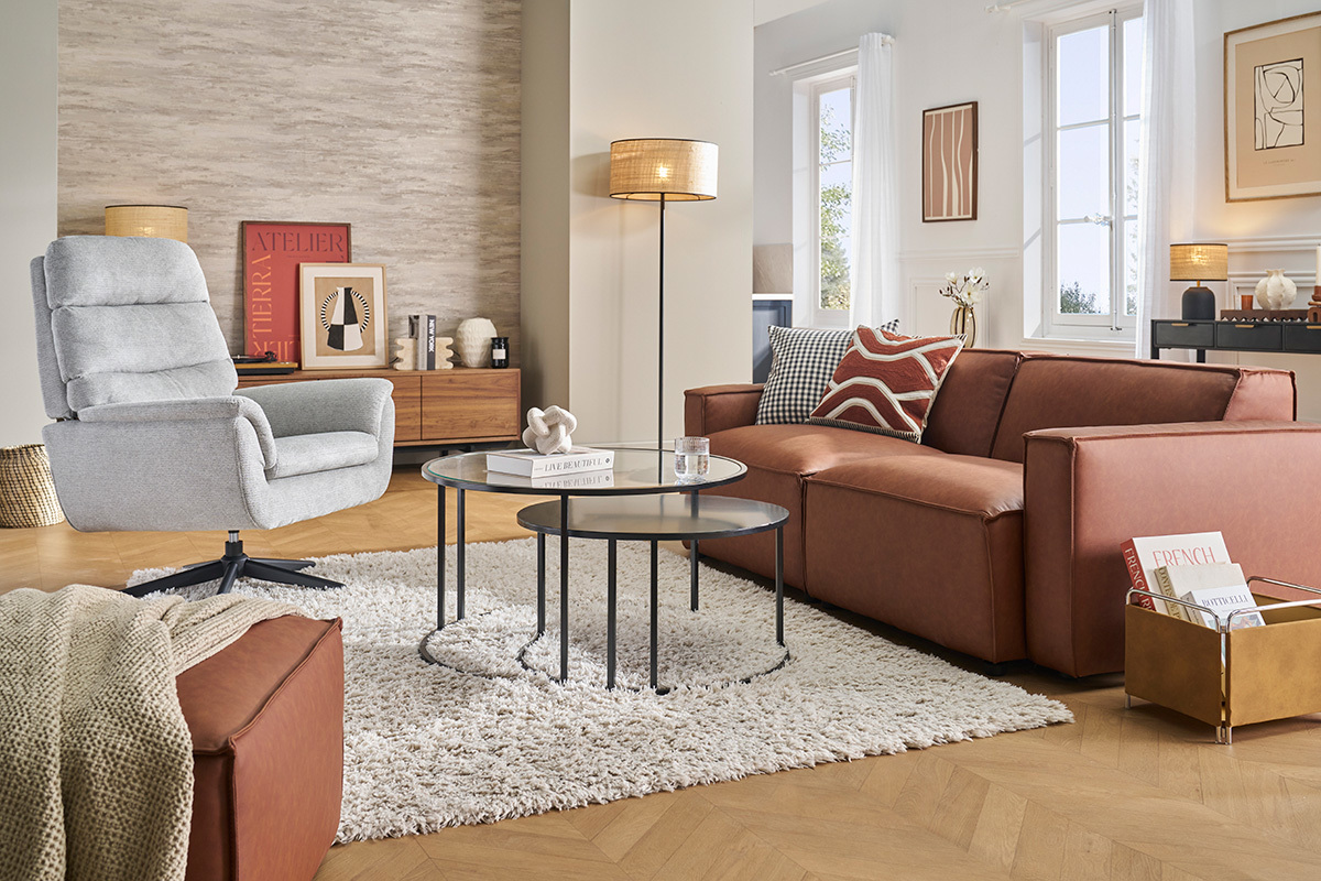 Fauteuil pivotant gris JONAH dans un salon moderne avec tables basses et canap� marron.