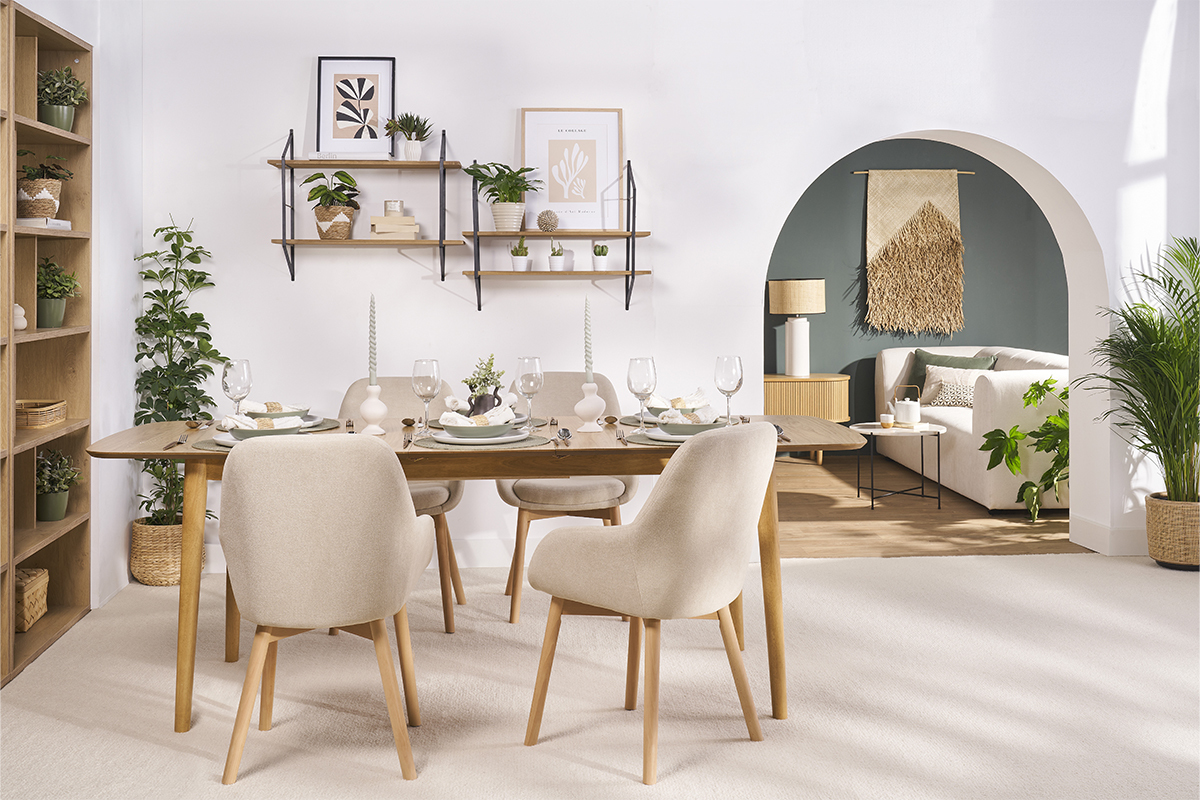 Salle � manger avec fauteuils scandinaves beige en tissu et pieds en bois clair autour d'une table.