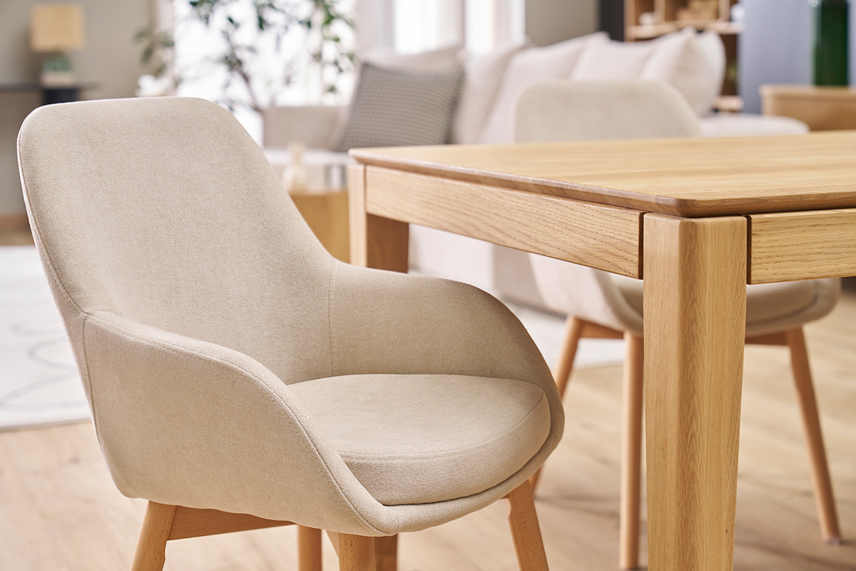 Fauteuil scandinave en tissu beige et bois clair, vue de profil, � c�t� d'une table en bois.