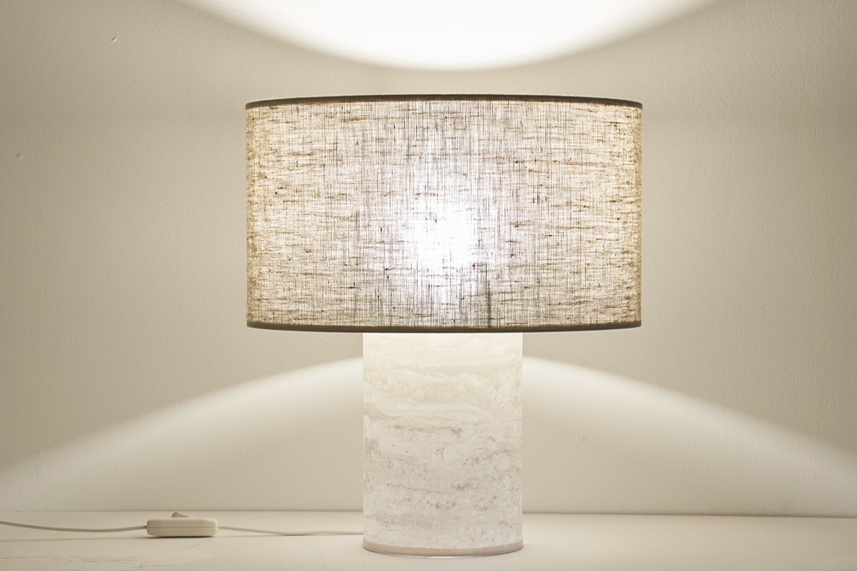 Lampe � poser design avec pied effet travertin et abat-jour en lin beige, vue de face, allum�e.