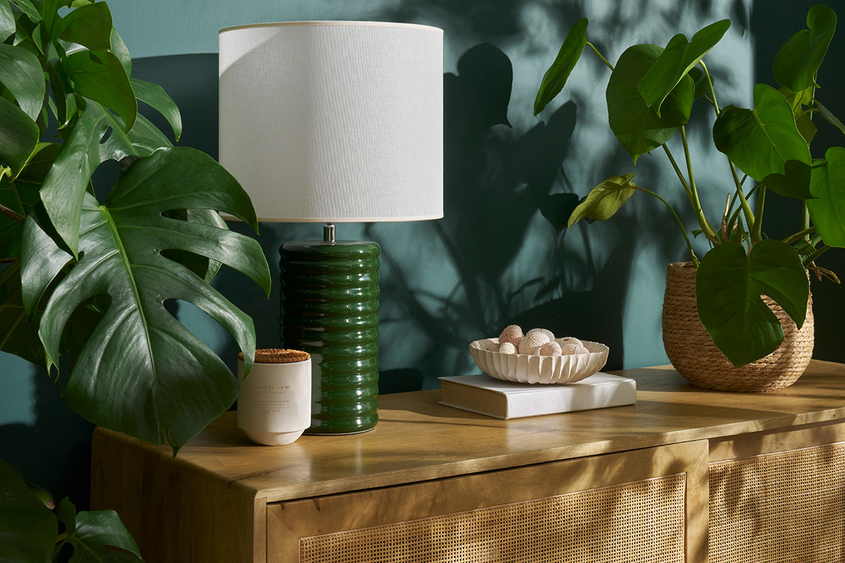 Lampe � poser en c�ramique verte avec abat-jour �cru, vue de face sur une console en bois.