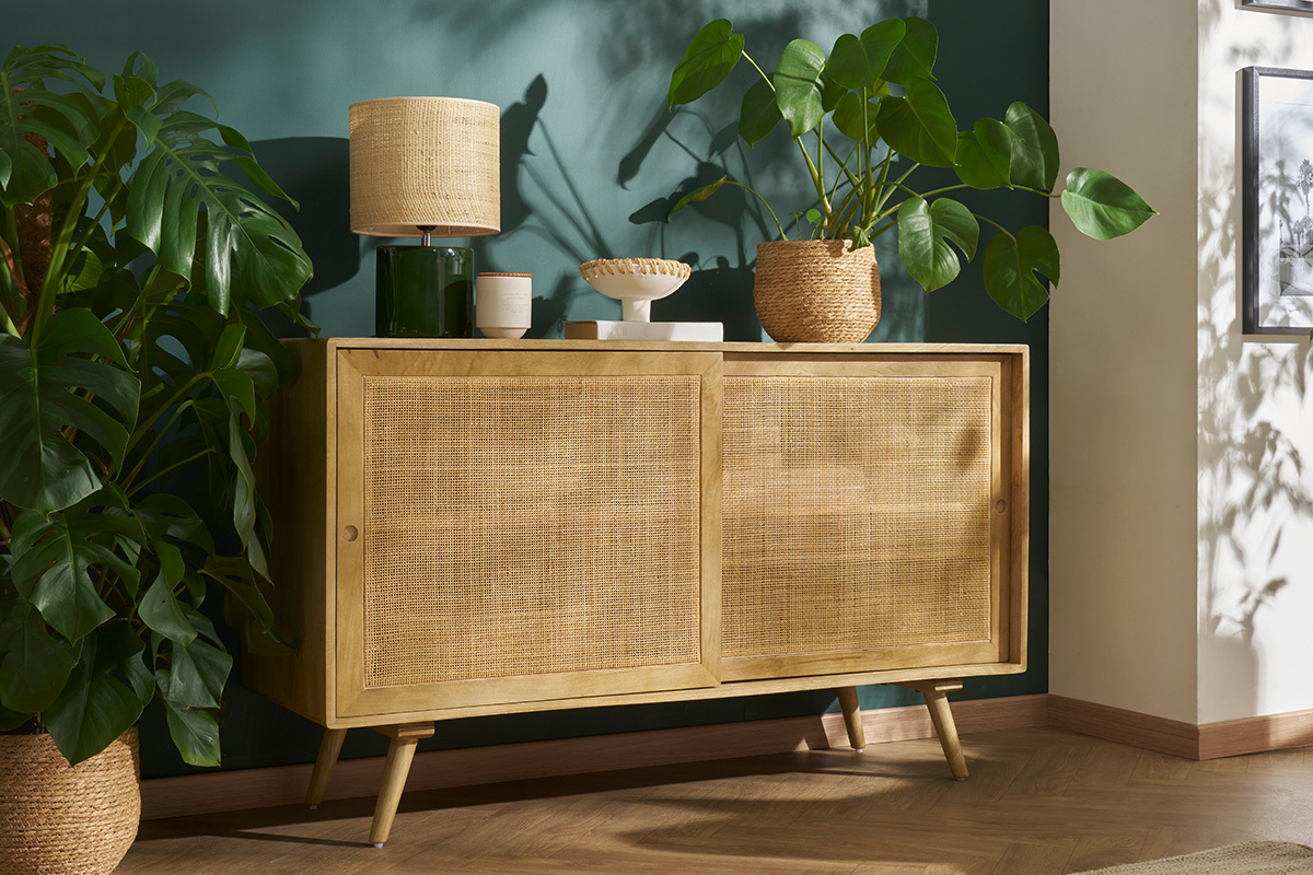 Lampe � poser c�ramique vert fonc� avec abat-jour en raphia, vue de profil, sur un meuble en bois.