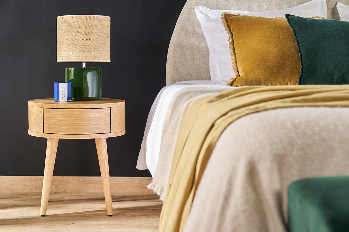Lampe � poser c�ramique vert fonc� avec abat-jour en raphia, vue de pr�s sur table de chevet.