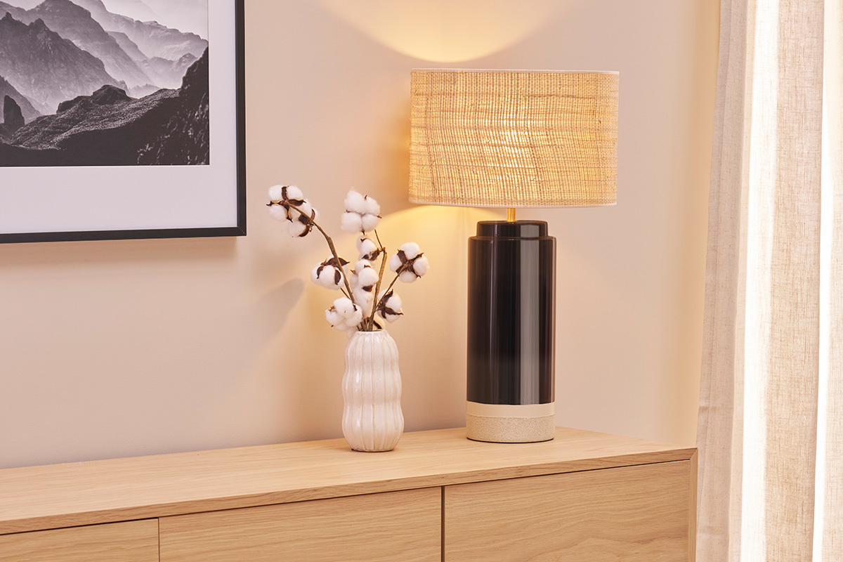 Lampe en c�ramique noire avec abat-jour rabane sur un buffet en bois.