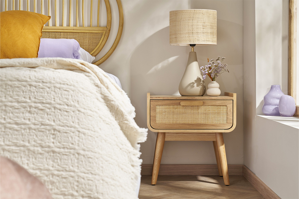Lampe en c�ramique taupe avec abat-jour en raphia sur table de chevet en bois.