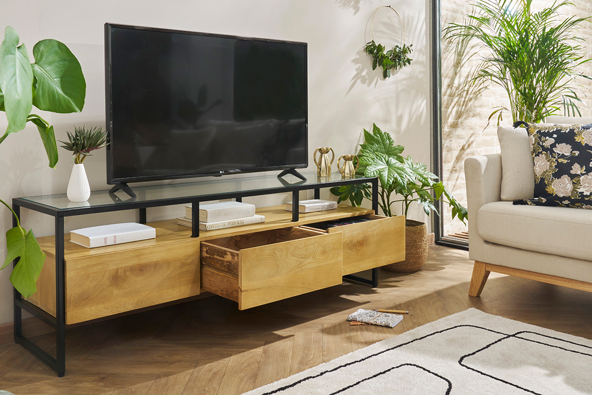 Meuble TV DIYA en bois manguier avec tiroirs ouverts et TV sur plateau en verre.