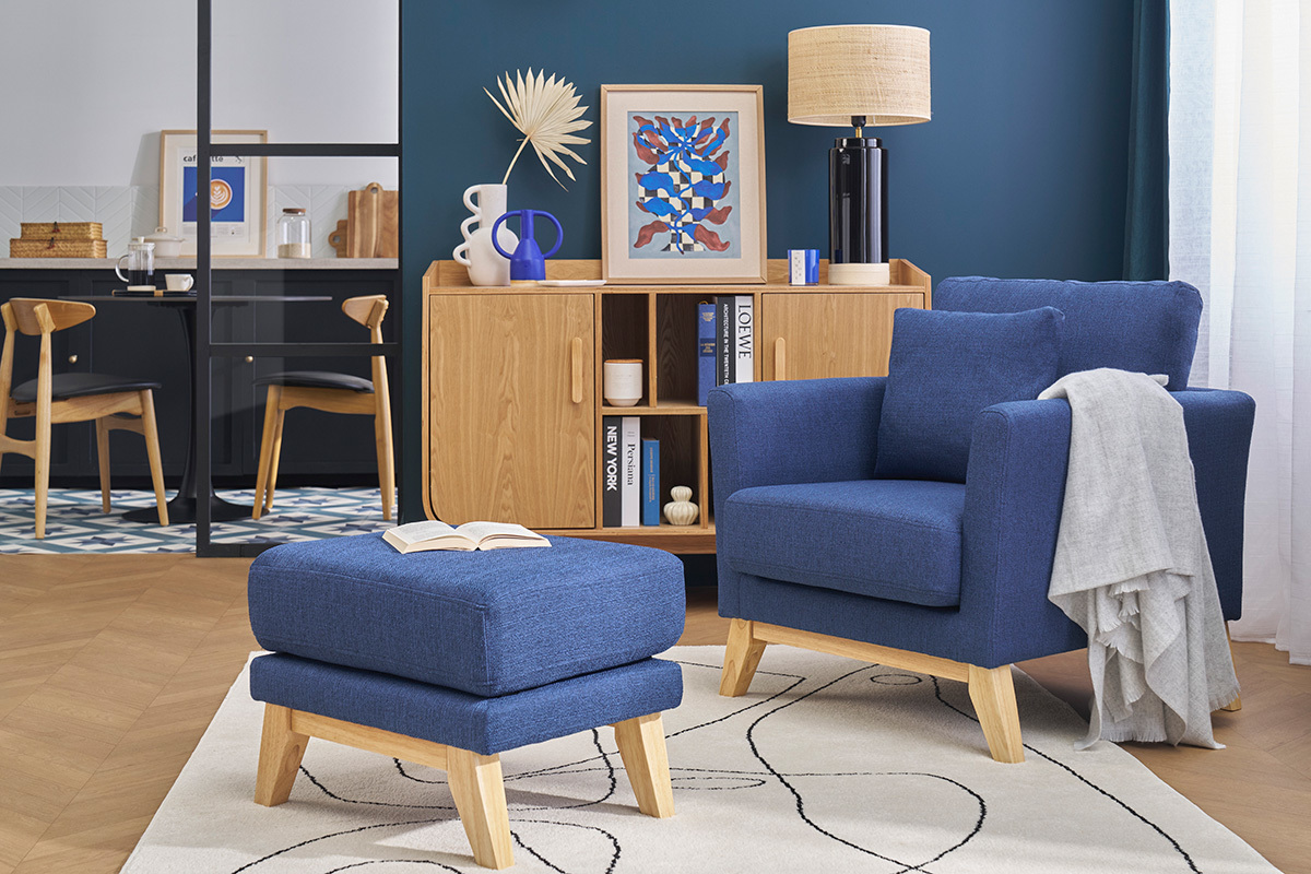 Pouf repose-pieds bleu fonc� et bois OSLO, vue de face, sur tapis avec fauteuil assorti.