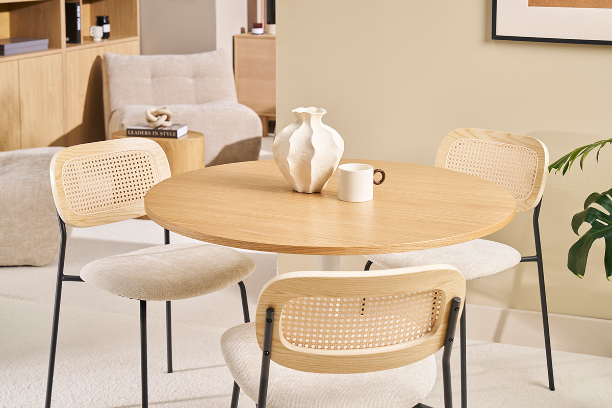 Table ronde en bois avec chaises en rotin, vase blanc et tasse, ambiance int�rieure moderne.