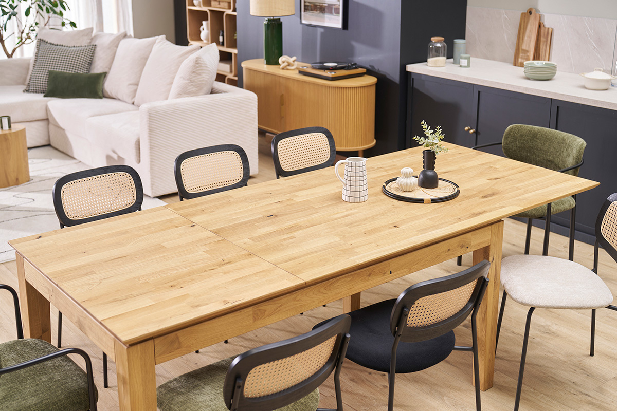 Table � manger extensible en ch�ne clair entour�e de chaises en rotin noir.