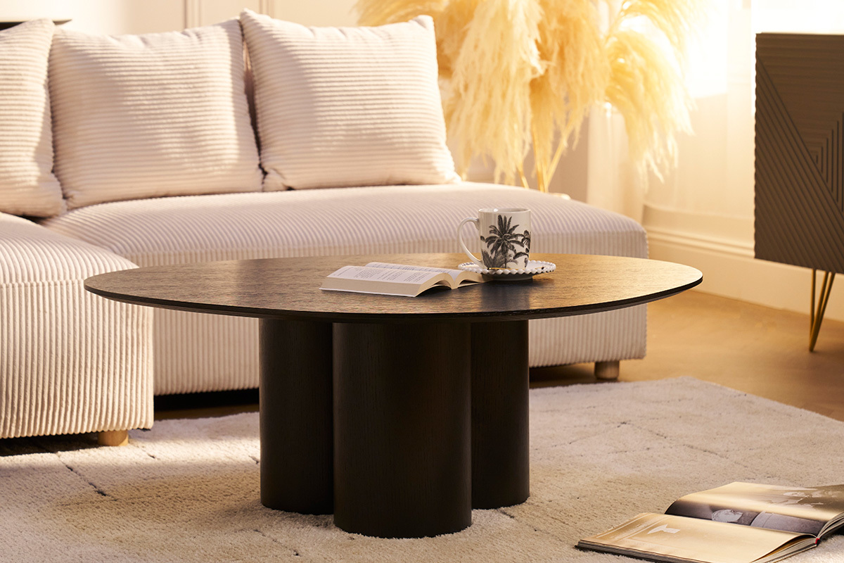 Table basse noire design HOLLEN avec magazines, tasse, sur tapis clair.