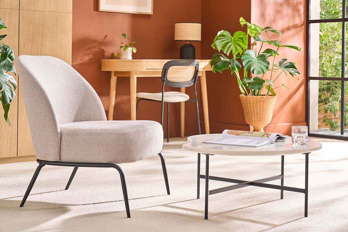 Table basse en marbre blanc et m�tal noir dans un salon avec fauteuil et plantes.