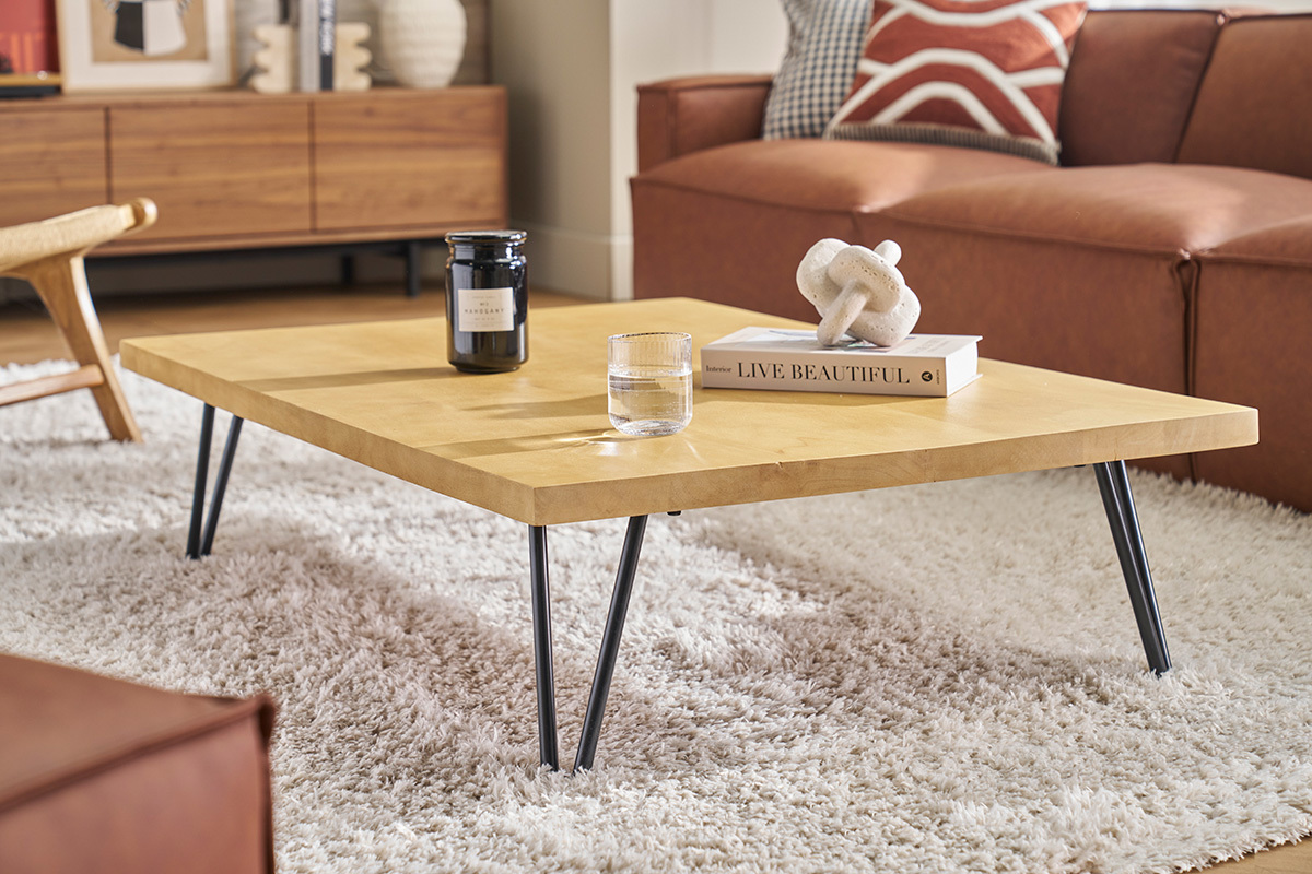 Table basse rectangulaire en bois de manguier sur tapis, vue de c�t� avec objets d�coratifs.