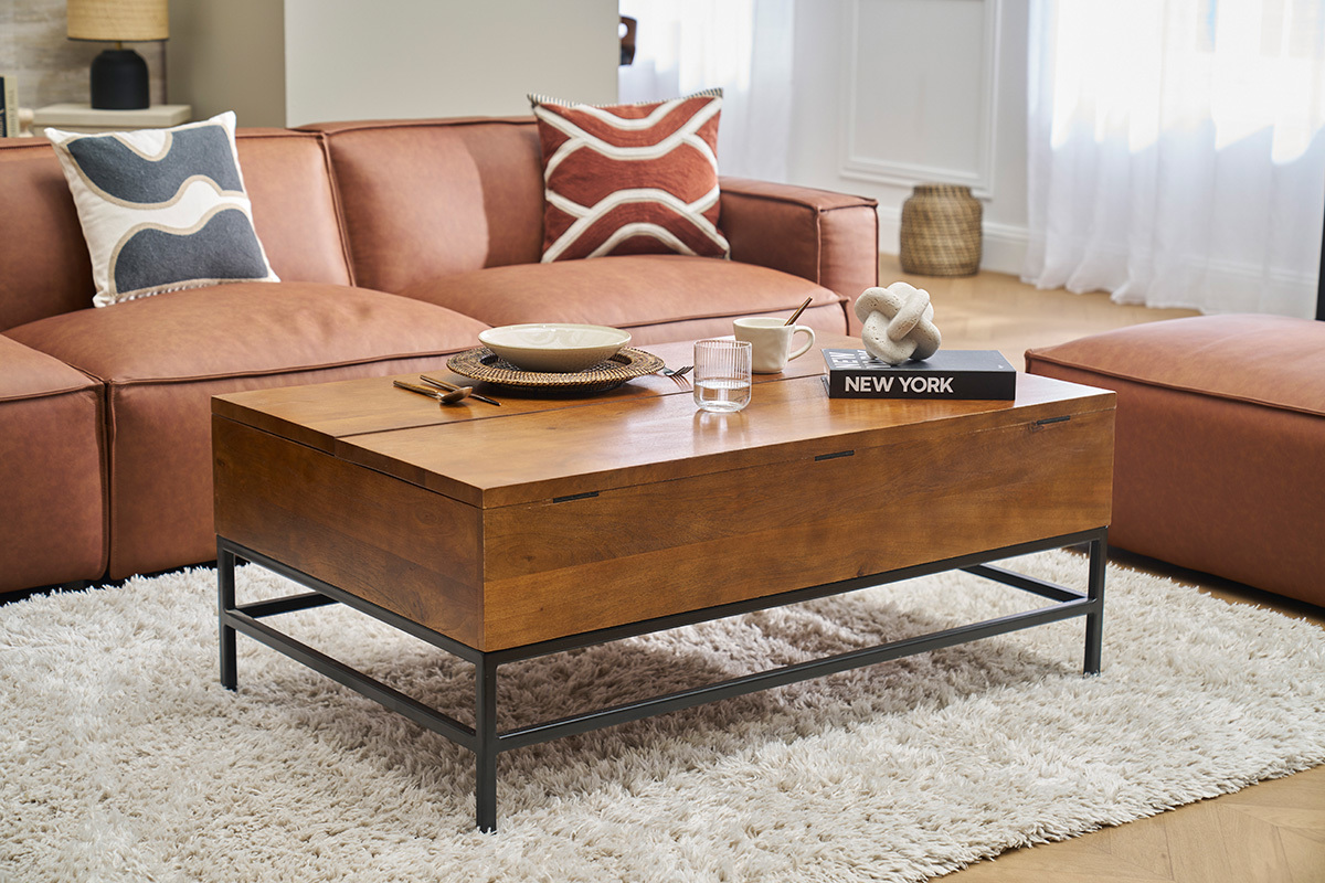 Table basse industrielle en bois et m�tal, devant un canap� marron, vue de 3/4, dans un salon.