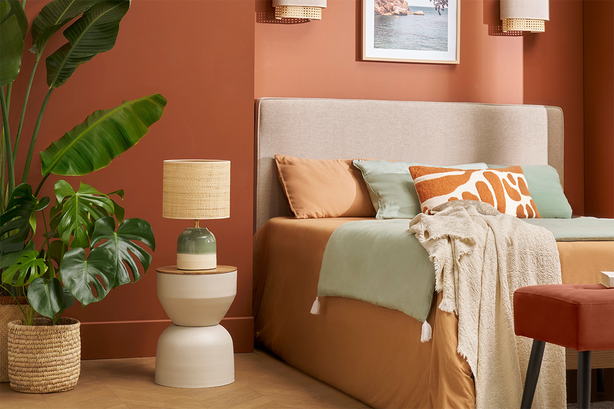 Table d'appoint YOYO en m�tal gr�ge et bois pr�s d'un lit, avec lampe et fleurs.