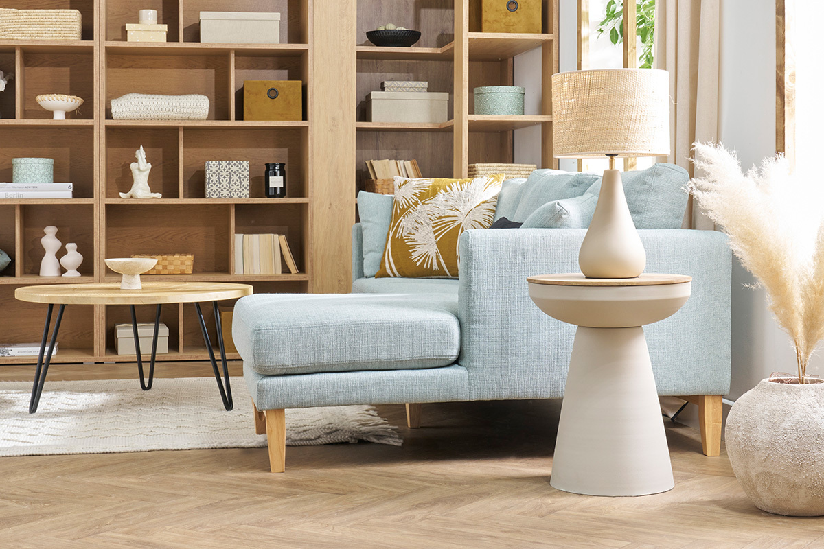 Table d'appoint ronde TAM en m�tal gr�ge et bois, � c�t� d'un canap� bleu.