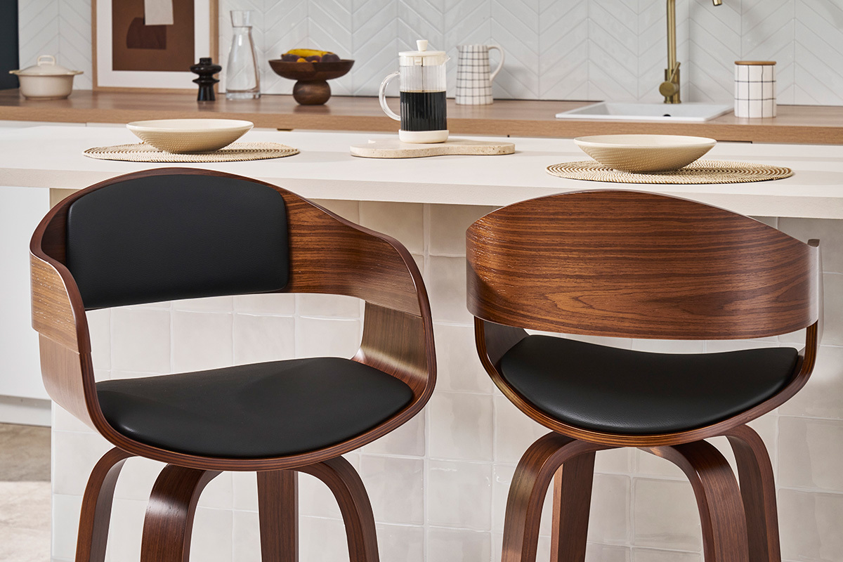 Deux tabourets de bar design noir et bois fonc�, vue de face, devant un comptoir de cuisine.