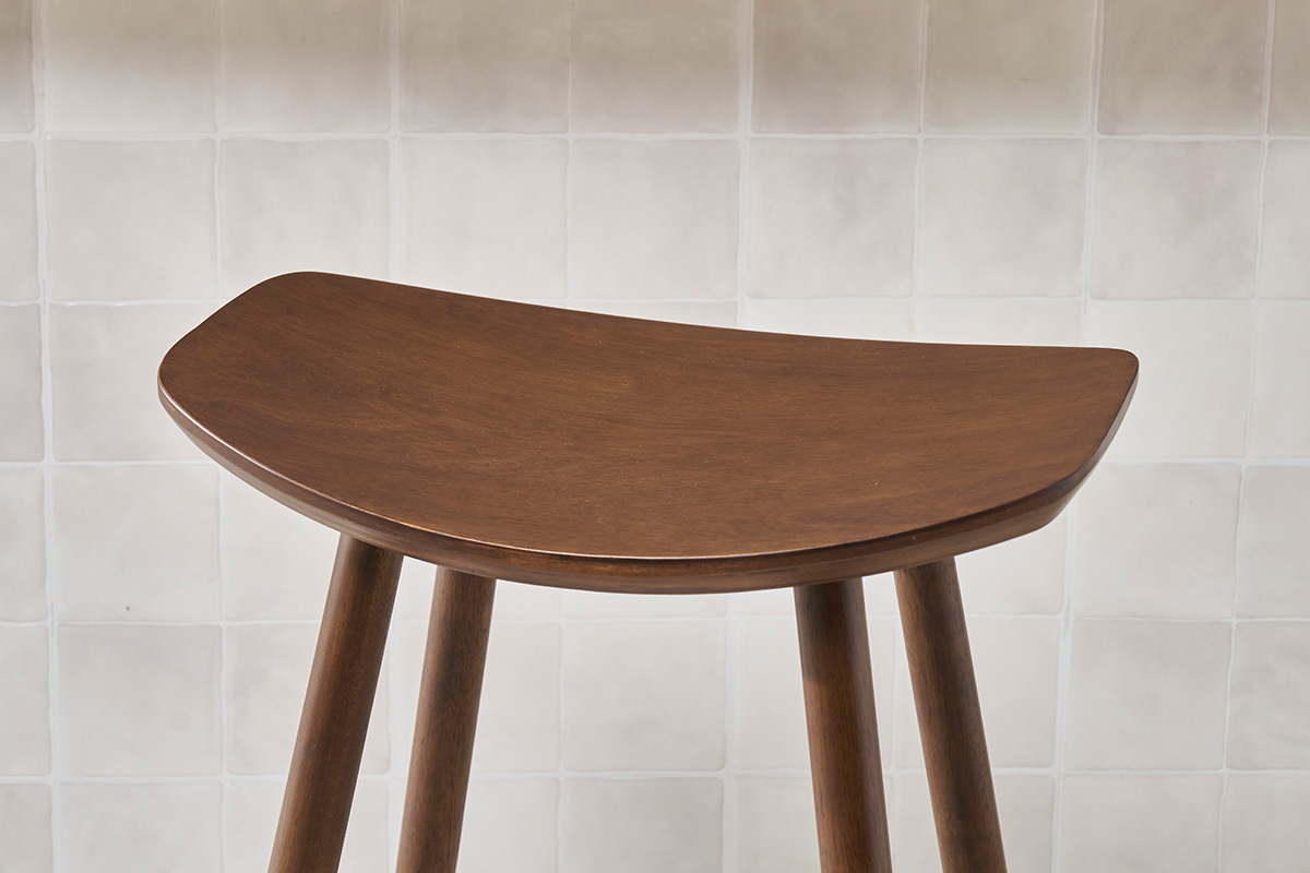 Tabouret de bar en bois sombre, vue de c�t�, avec assise incurv�e et pieds cylindriques.
