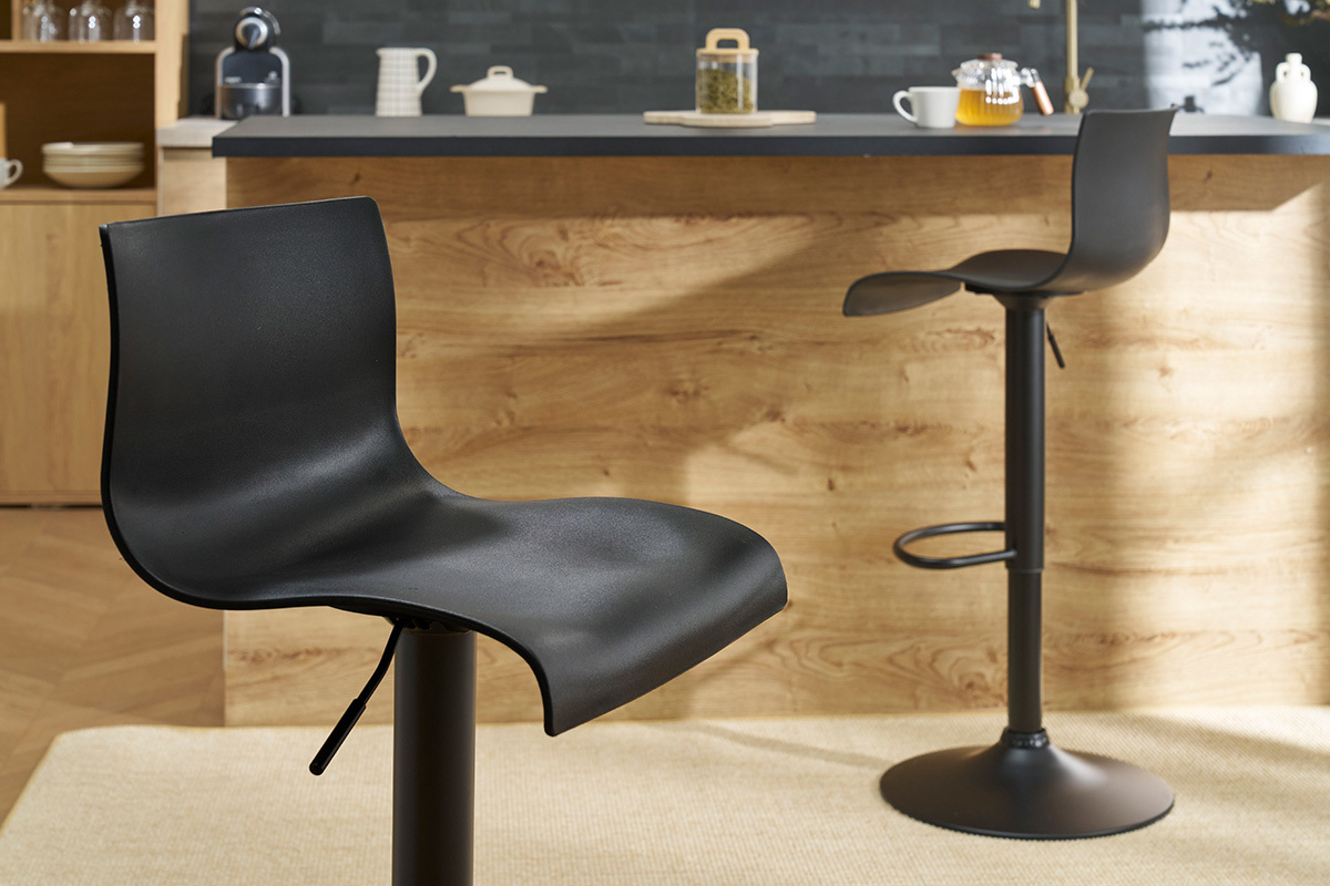 Tabourets de bar noirs en m�tal r�glables devant un comptoir, vue zoom�e.