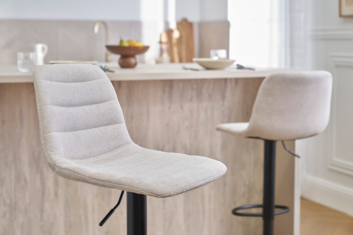 Tabourets de bar r�glables en tissu beige et m�tal noir devant un comptoir.