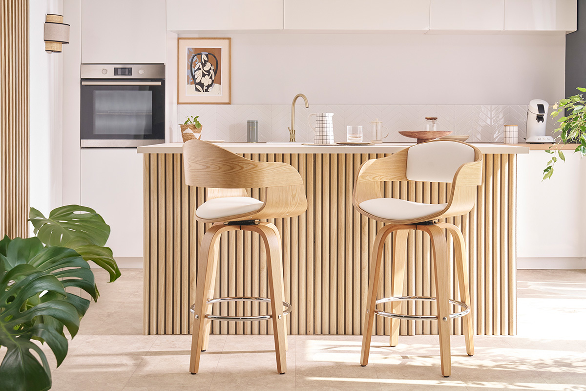 Deux tabourets de bar scandinaves en bois clair devant un comptoir de cuisine.