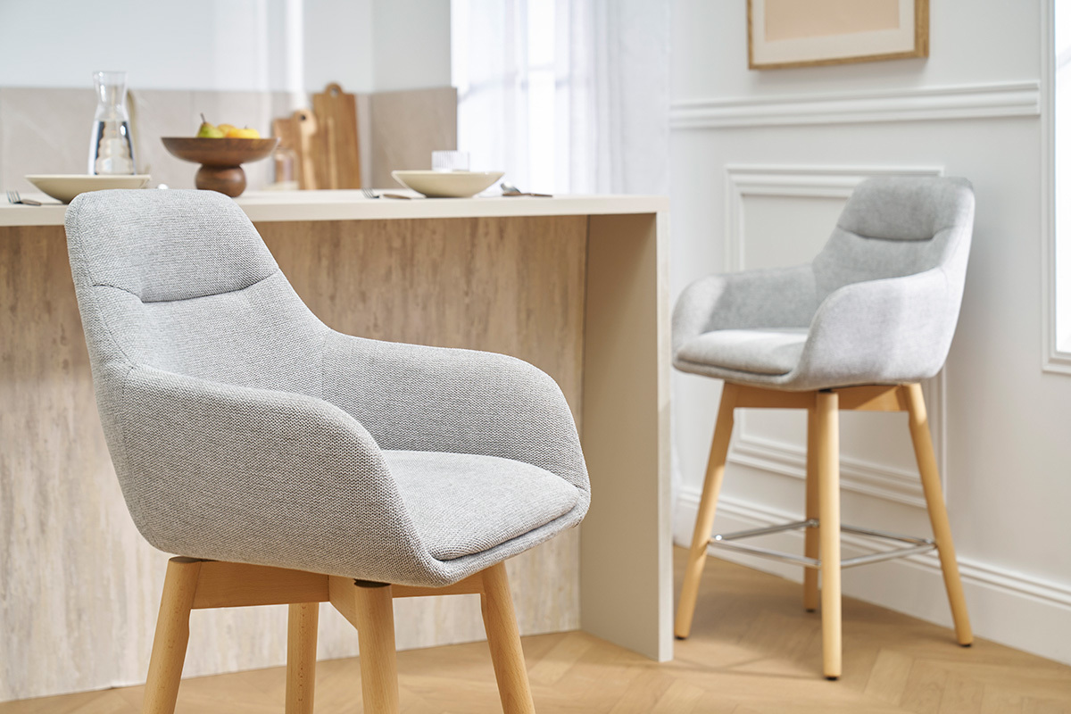 Tabourets de bar scandinaves gris clair en tissu et bois clair, vue de profil.