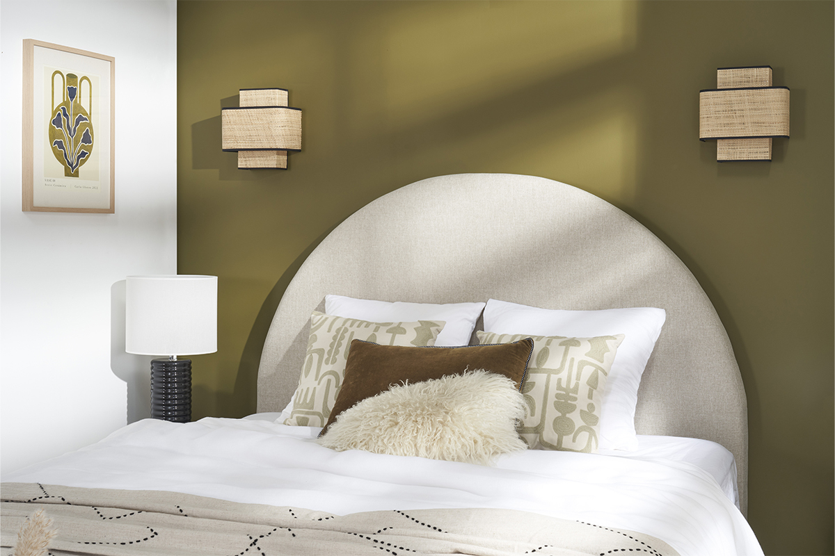 T�te de lit ronde beige dans une chambre avec lampes et coussins. Mur kaki.