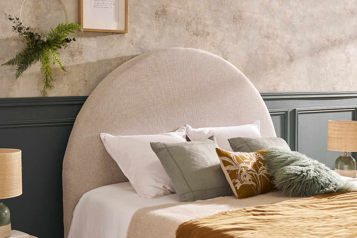 T�te de lit ronde en tissu beige avec oreillers multicolores et lampes, vue de face.