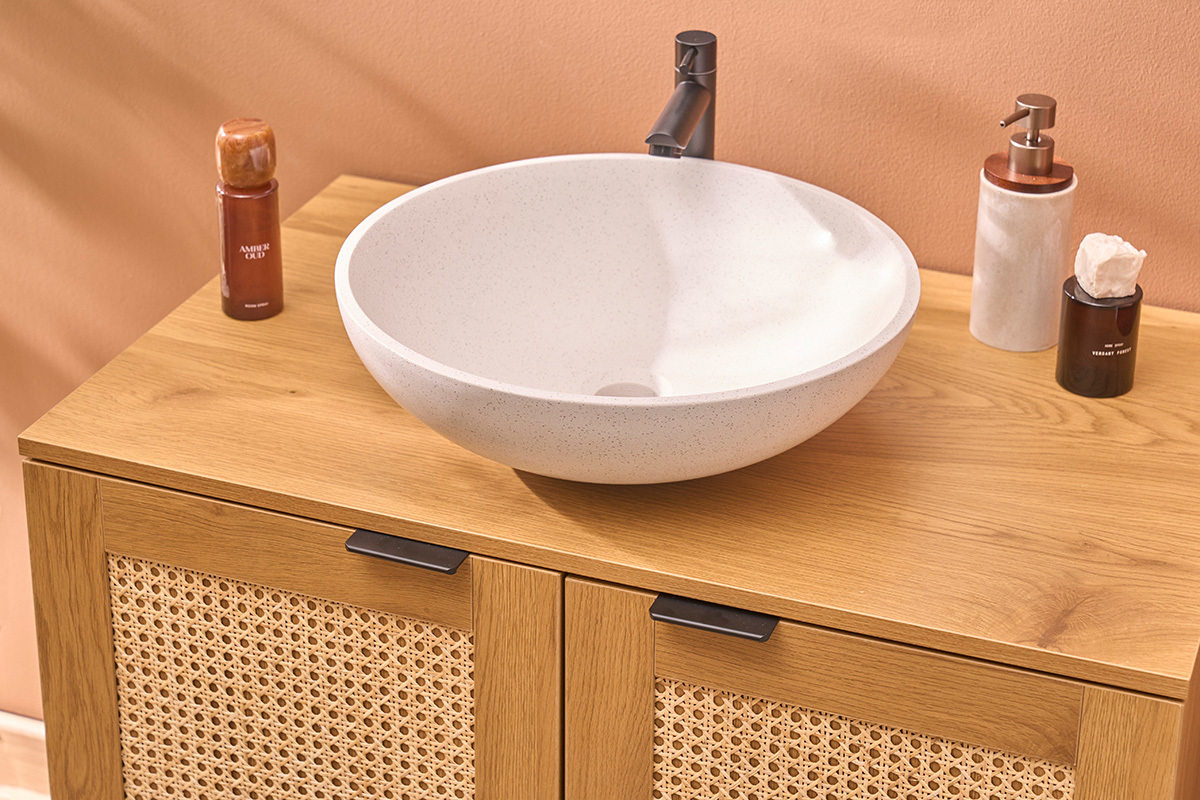 Vasque ronde en terrazzo gris de 40 cm sur un meuble en bois avec divers produits de bain